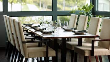 Una mesa de comedor preparada para seis personas, con sillas, vista por la ventana y una planta al fondo.
