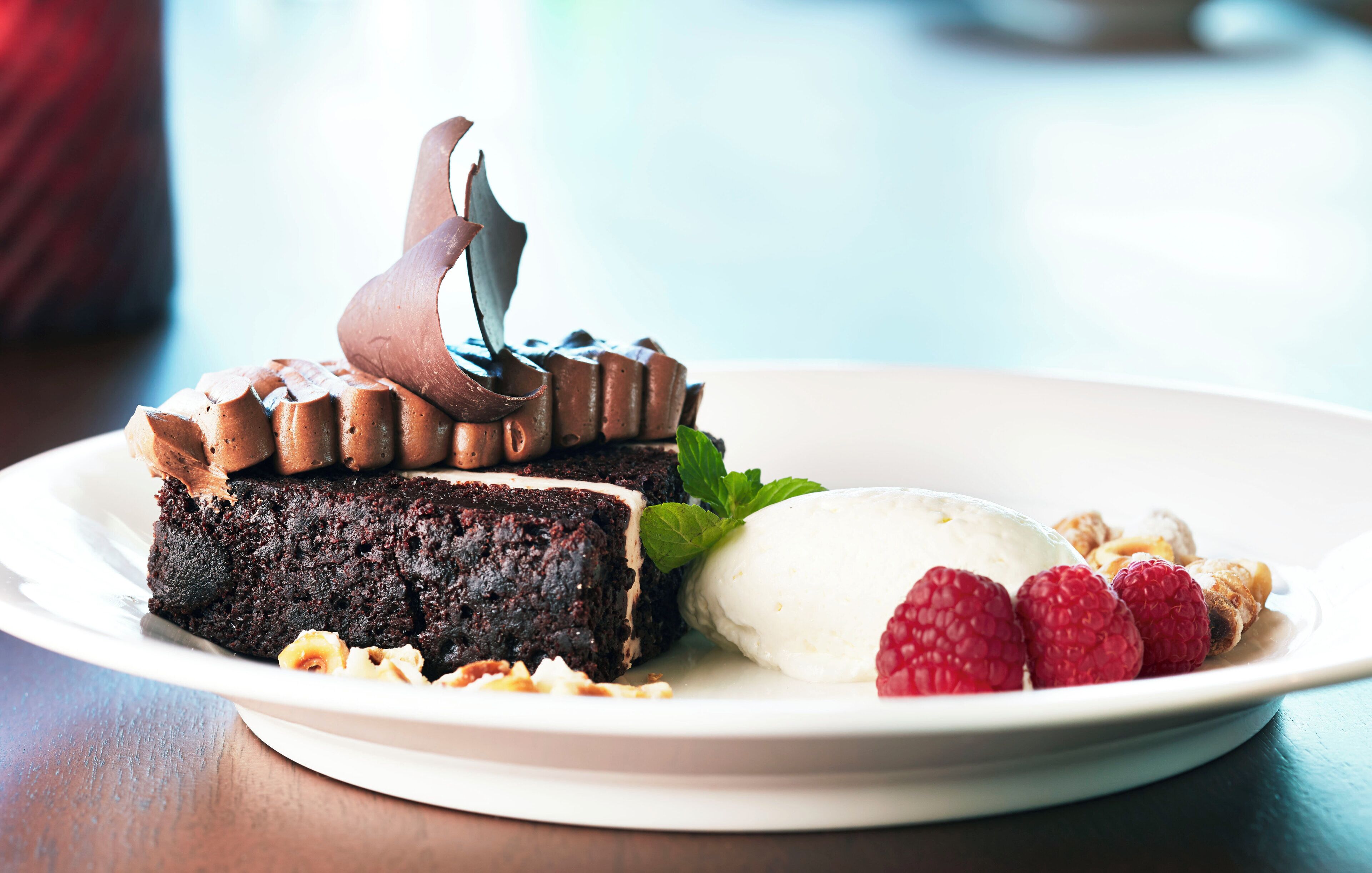 A plate with a slice of chocolate cake, a scoop of ice cream, and fresh raspberries.