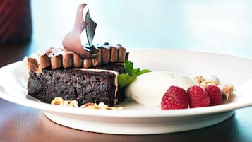 A plate with a slice of chocolate cake, a scoop of ice cream, and fresh raspberries.
