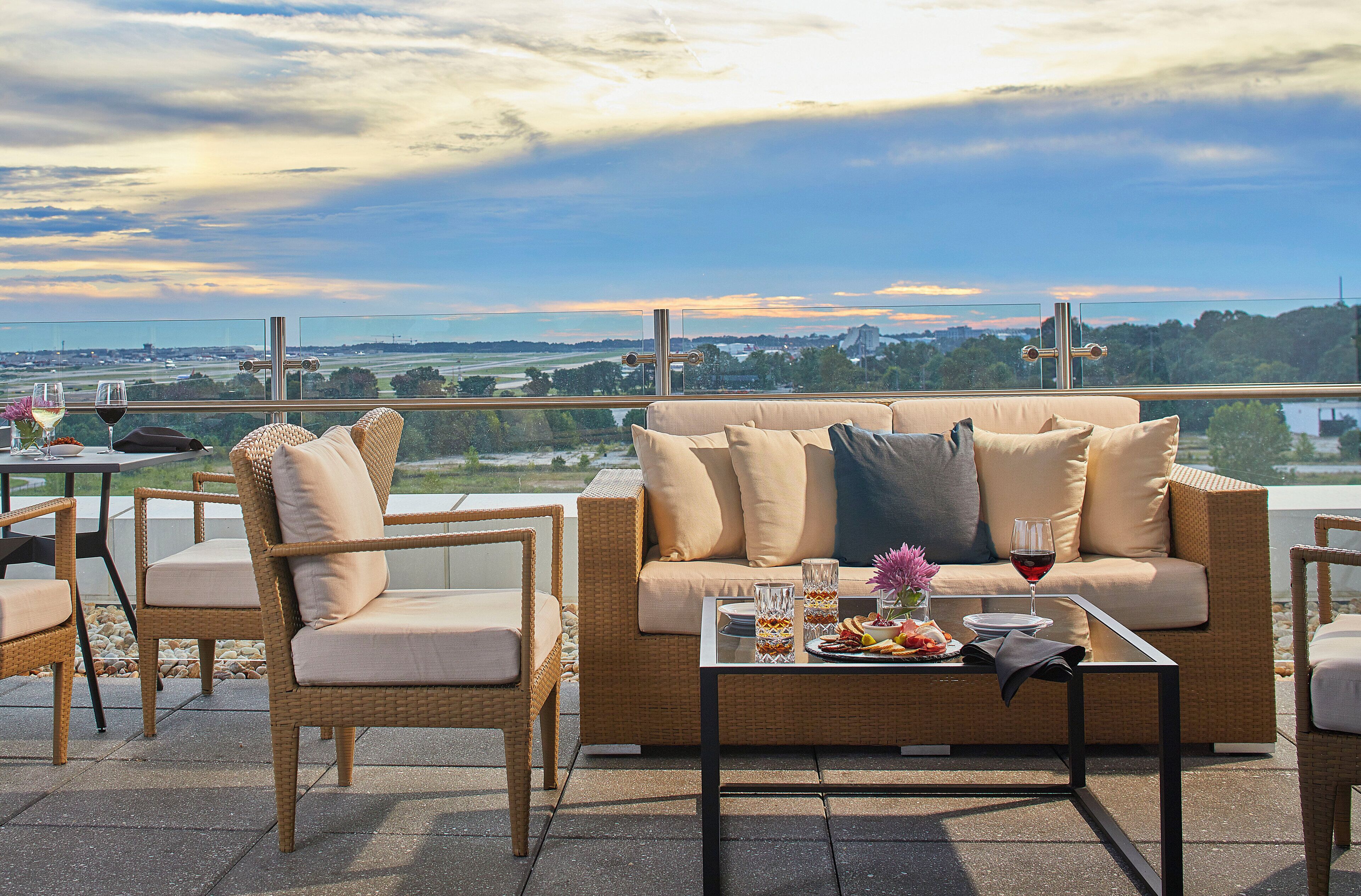 Una terraza con mobiliario de mimbre, una mesa de vidrio y vistas al paisaje.