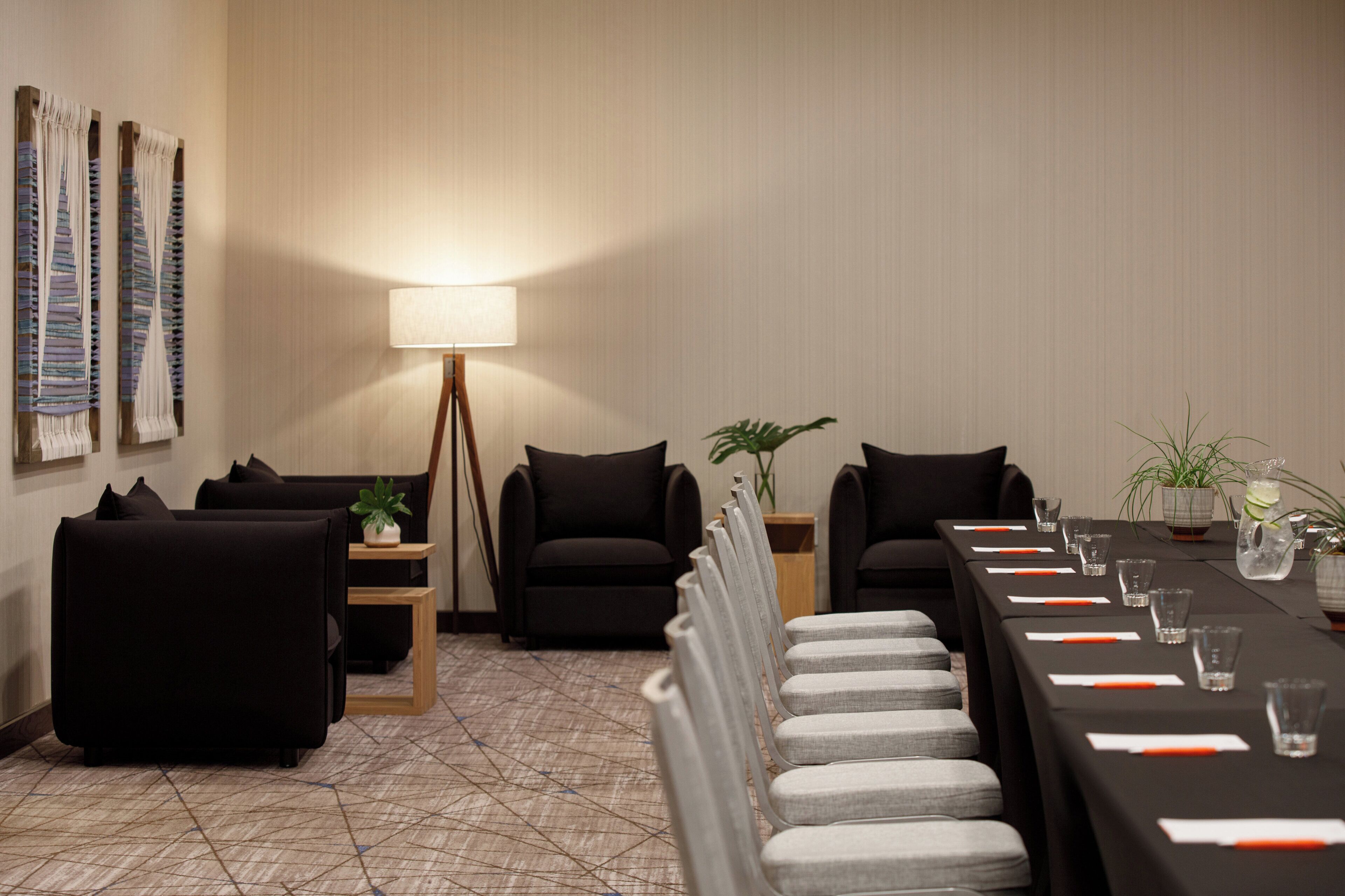 A conference room with a long table, chairs, a lamp, and decorative wall panels.