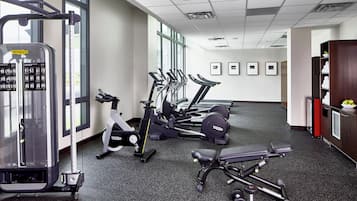 Une salle de sport équipée de divers appareils d’exercice, notamment des tapis de course et des appareils de musculation, ainsi qu’un mur orné de tableaux.