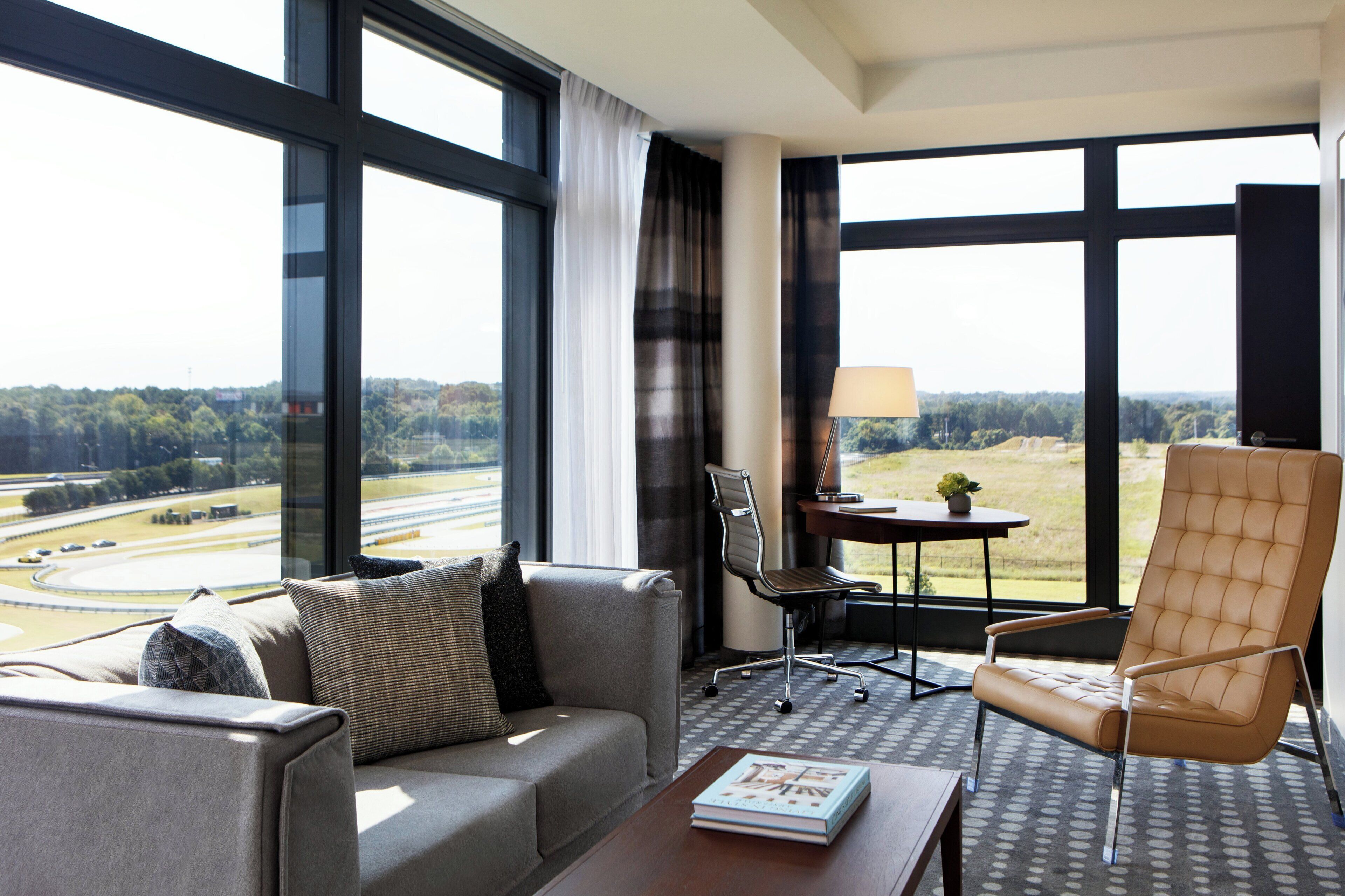 A modern hotel room with a large window offering a view of a highway and greenery.