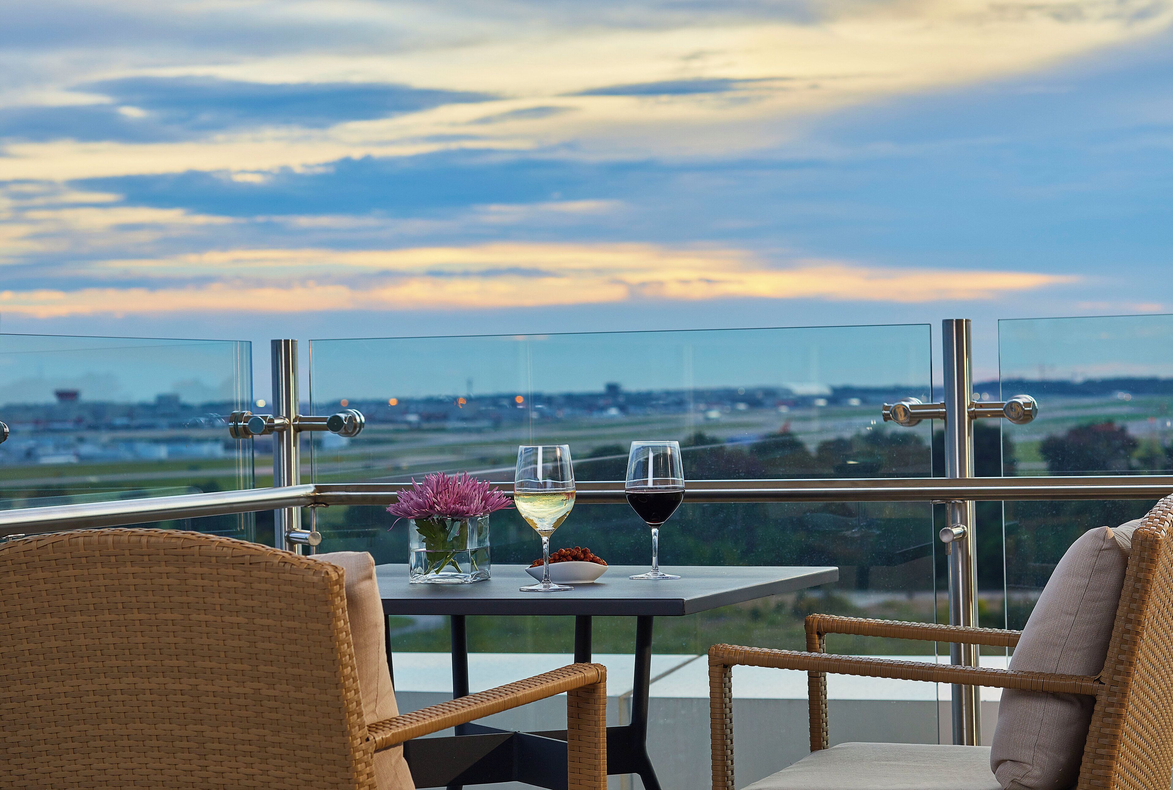 A balcony with a table, two chairs, and two wine glasses.