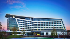 Ein modernes Hotel mit gebogener Fassade, mehreren Etagen und einem markanten Eingang.