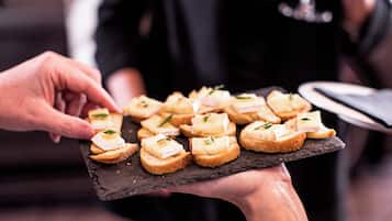 A person holding a slate board with small appetizers.
