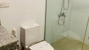 Ein Badezimmer mit Toilette, Dusche und einer Arbeitsplatte aus Granit.
