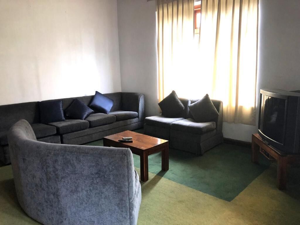 A living room with a sofa, armchair, and a television.