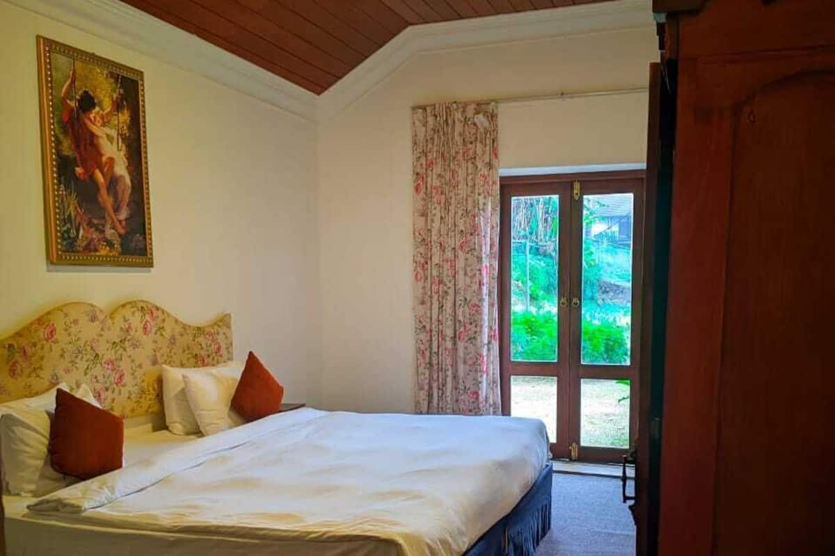Une chambre Ă coucher avec un lit, un tableau, une porte donnant sur lâextĂ©rieur et un sol recouvert de moquette.