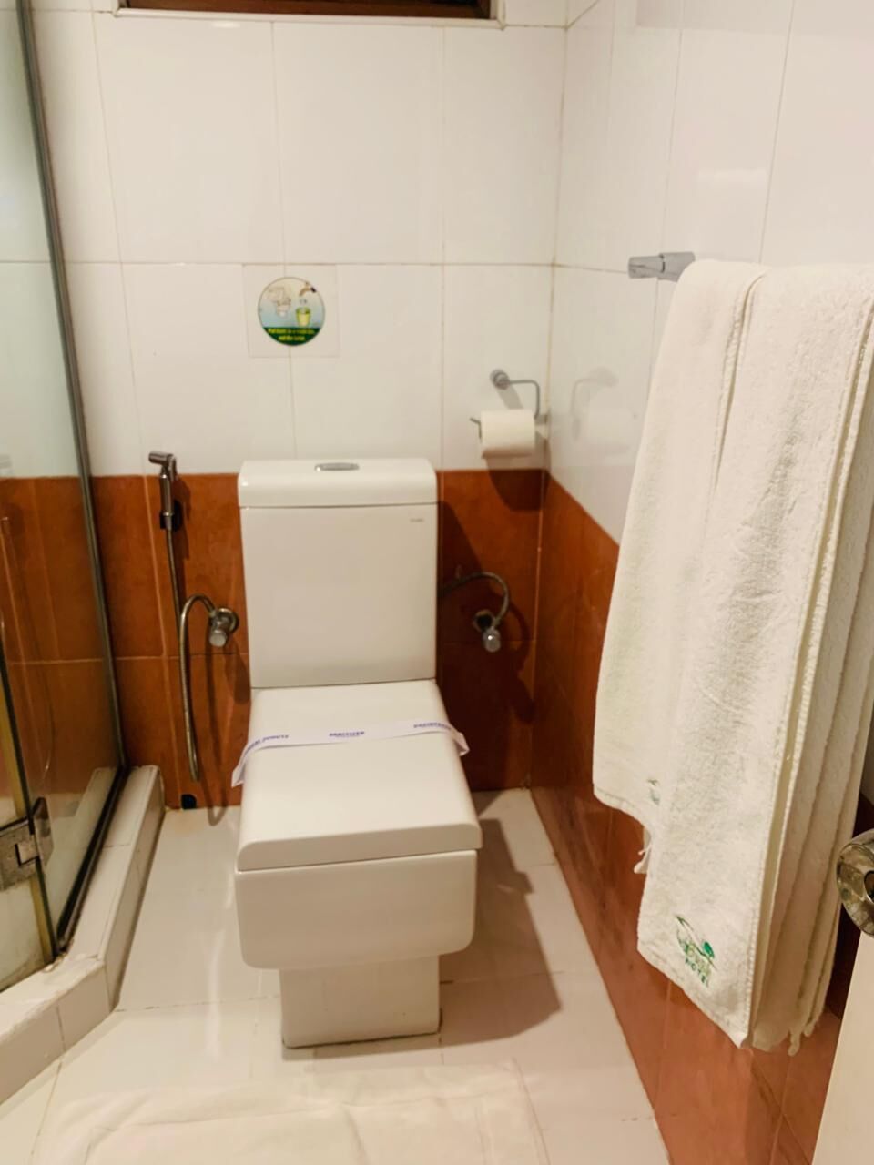 Une salle de bain comprenant des toilettes, un espace douche et un porte-serviettes.