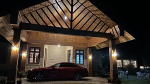 Un coche rojo estacionado bajo una zona cubierta de madera con paredes de piedra y suelo de ladrillo.