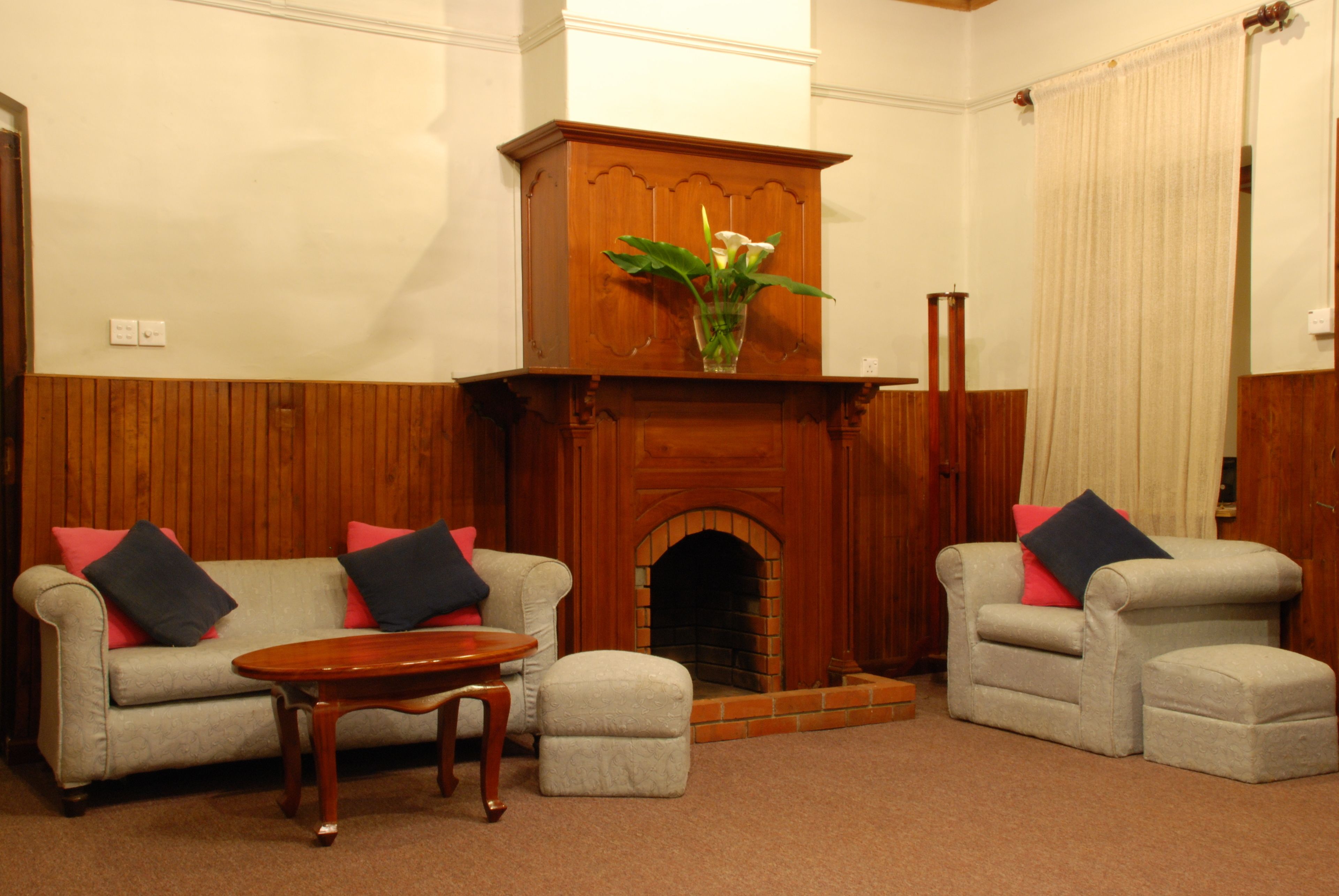 A living room with two armchairs, a sofa, a wooden coffee table, and a fireplace.