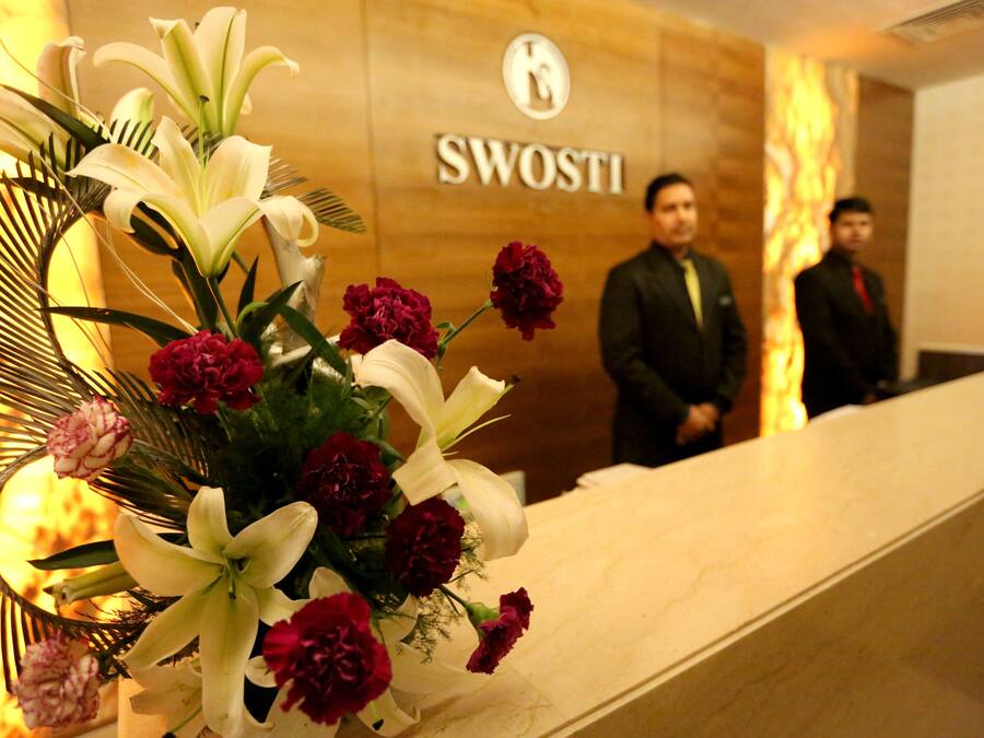 Un mostrador de recepción con un arreglo floral y un cartel que dice 'SWOSTI'.