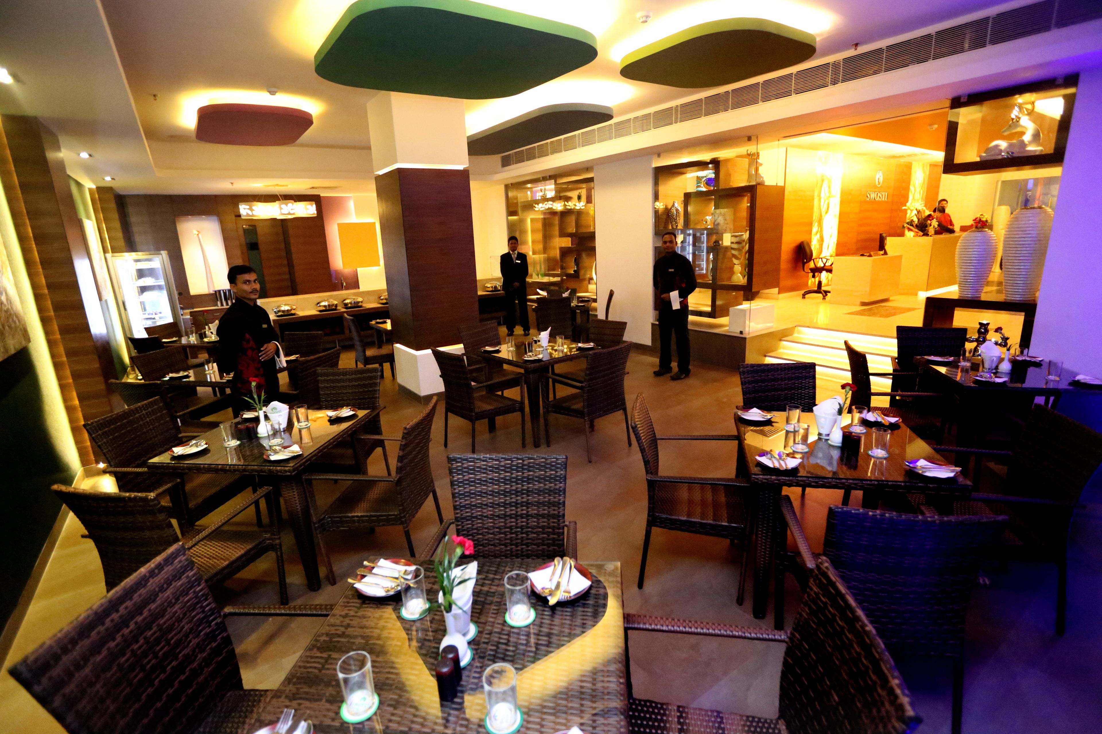 A restaurant with multiple dining tables and chairs, a bar area, and a reception desk.