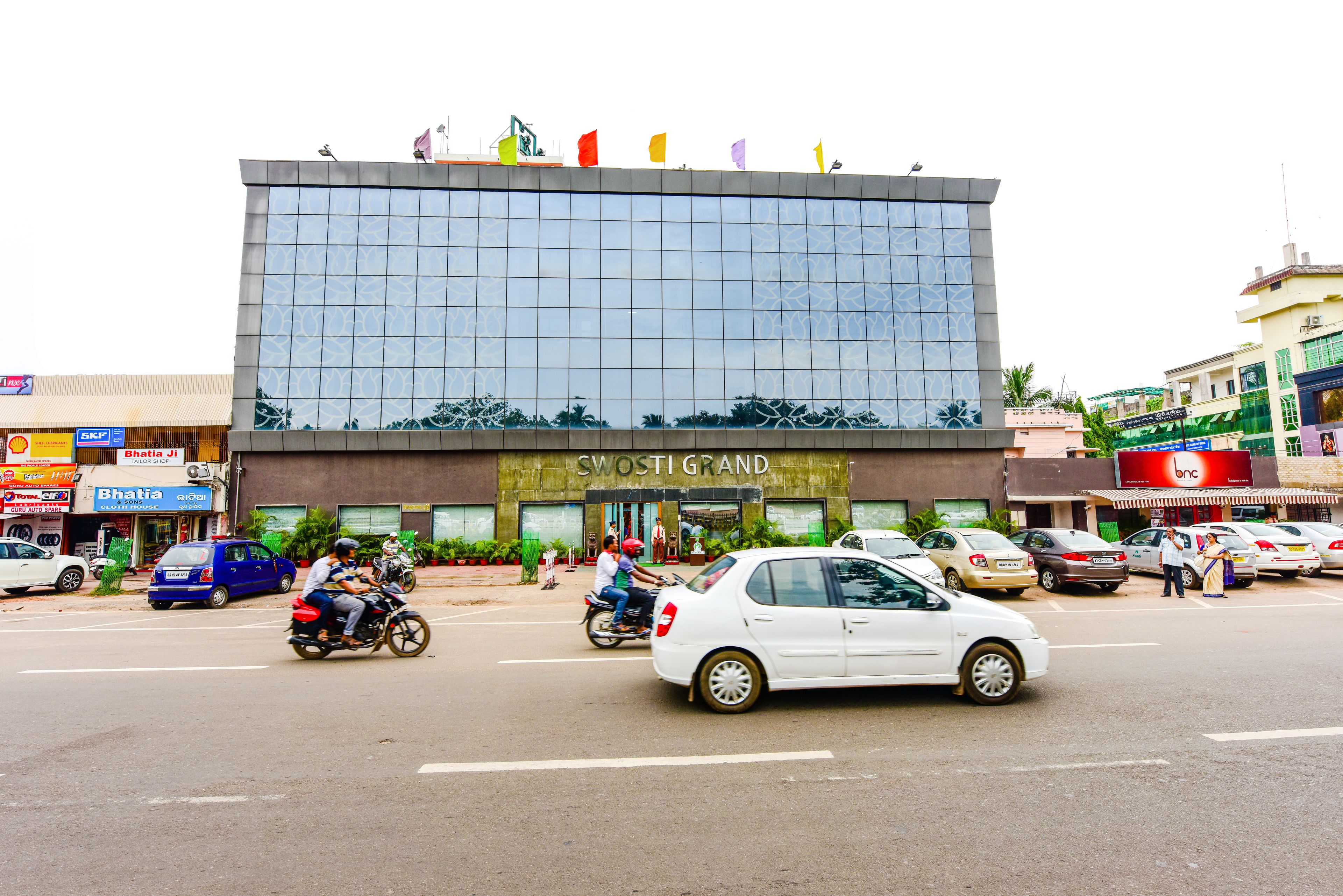 A modern building with a large glass facade and the name "SWOSTI GRAND" prominently displayed.