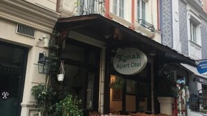 Un immeuble avec une enseigne indiquant « Konak Apart Otel » et un balcon orné de plantes suspendues.