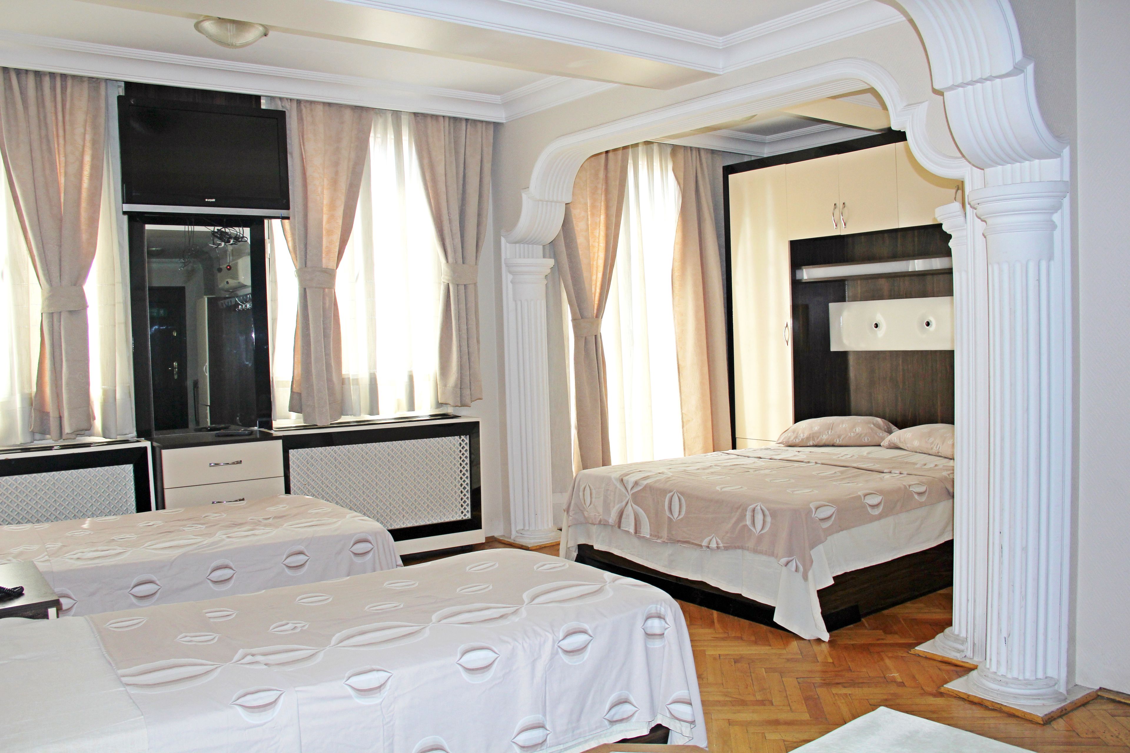 A hotel room with two beds, a TV, a desk, and a wardrobe.