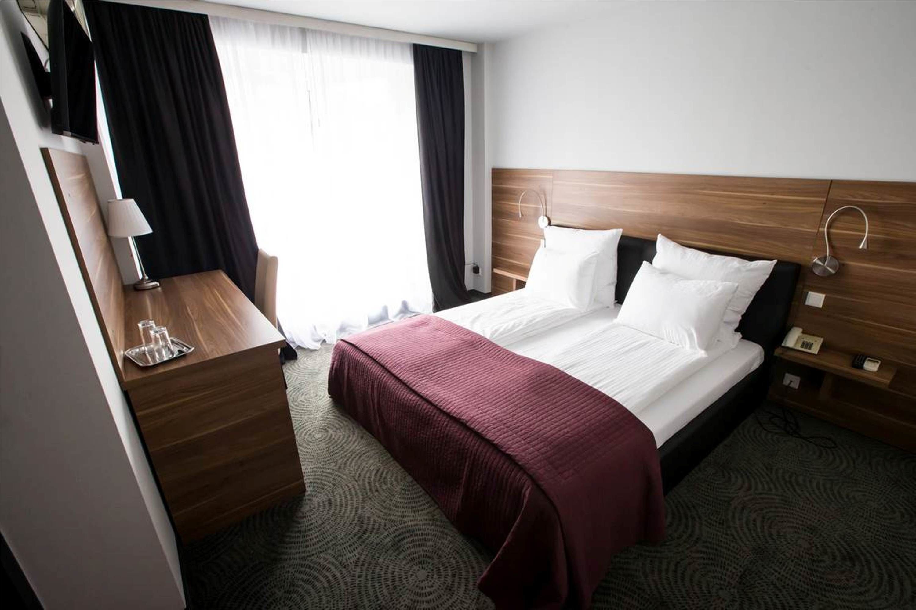 Una habitación de hotel con una cama, un escritorio, una lámpara y un televisor.