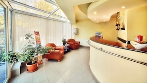 A reception area with a curved counter, seating, and a potted plant. - President Hotel (Timisoara)