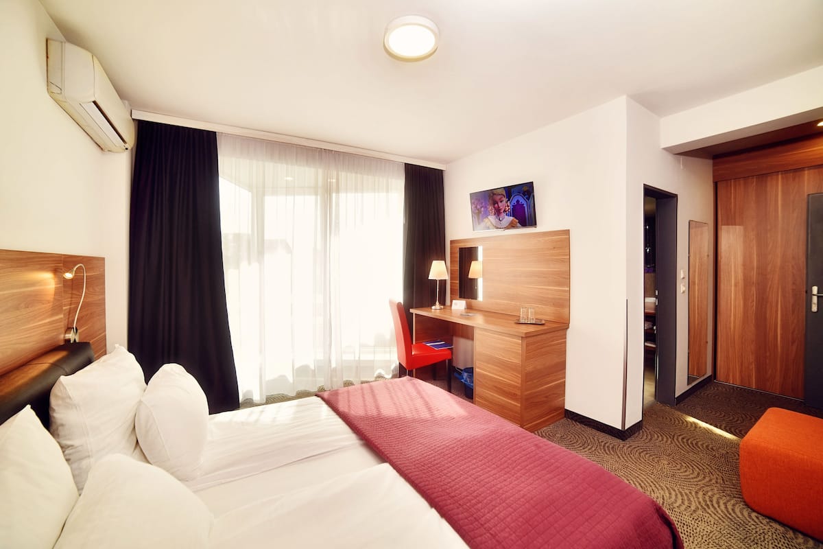 A hotel room with a bed, desk, chair, and wardrobe.
