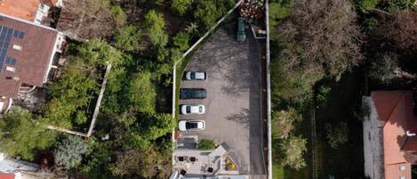 An aerial view of a residential area with a parking lot, three cars, and surrounding greenery.