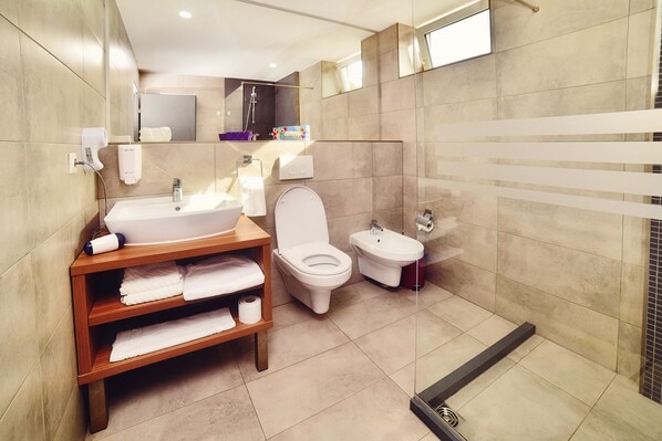 A modern bathroom with a sink, toilet, bidet, and a shower area. - President Hotel (Timisoara)