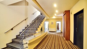 A hotel hallway with a striped carpet, a staircase with metal railings, and a door marked with the number 104. - President Hotel (Timisoara)