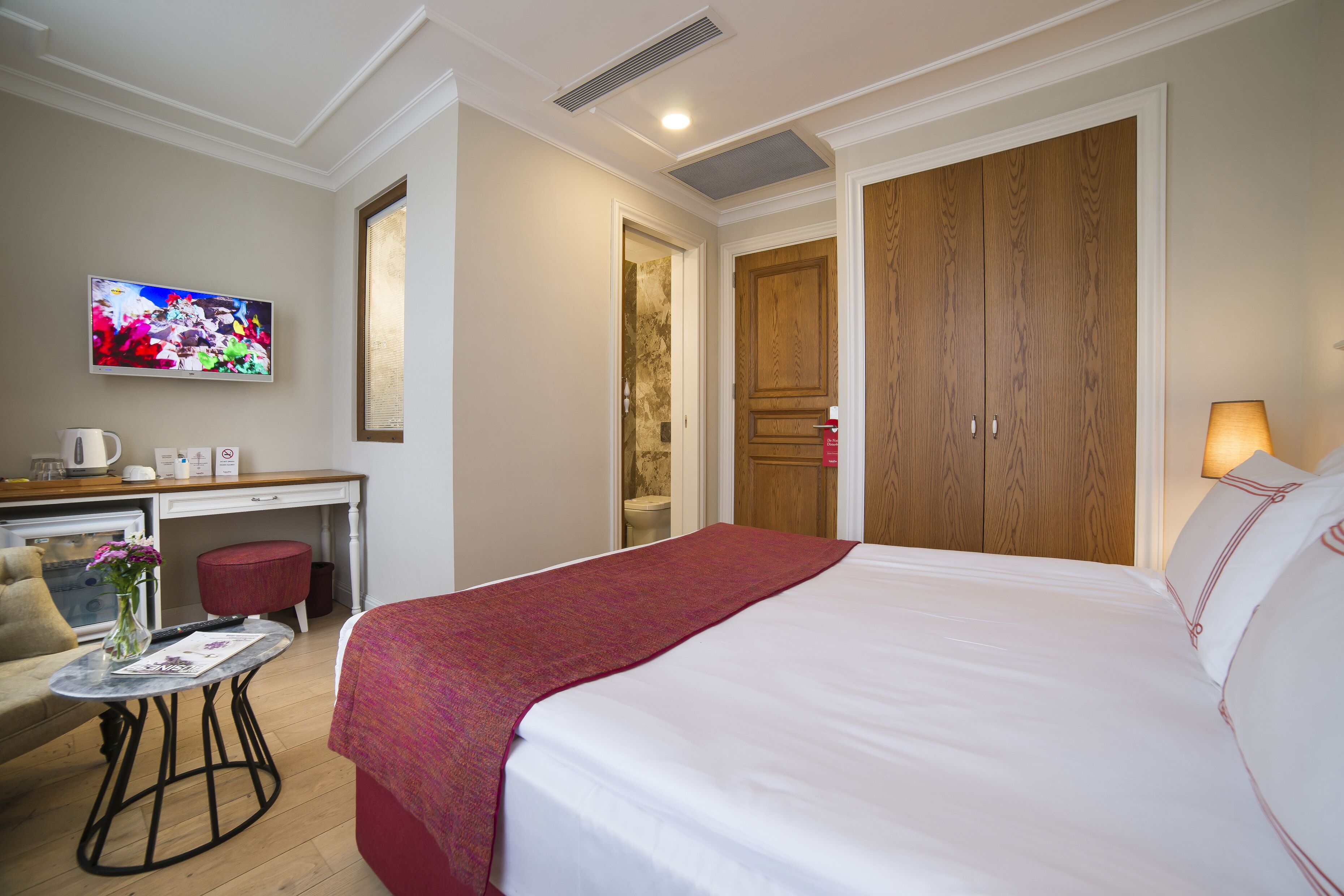 Una camera d'albergo con un letto, una scrivania, una televisione e un bagno.