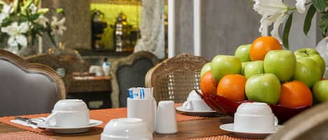 Een ontbijtsetting met een gedekte tafel voor twee, inclusief borden, kopjes en een schaal met fruit.