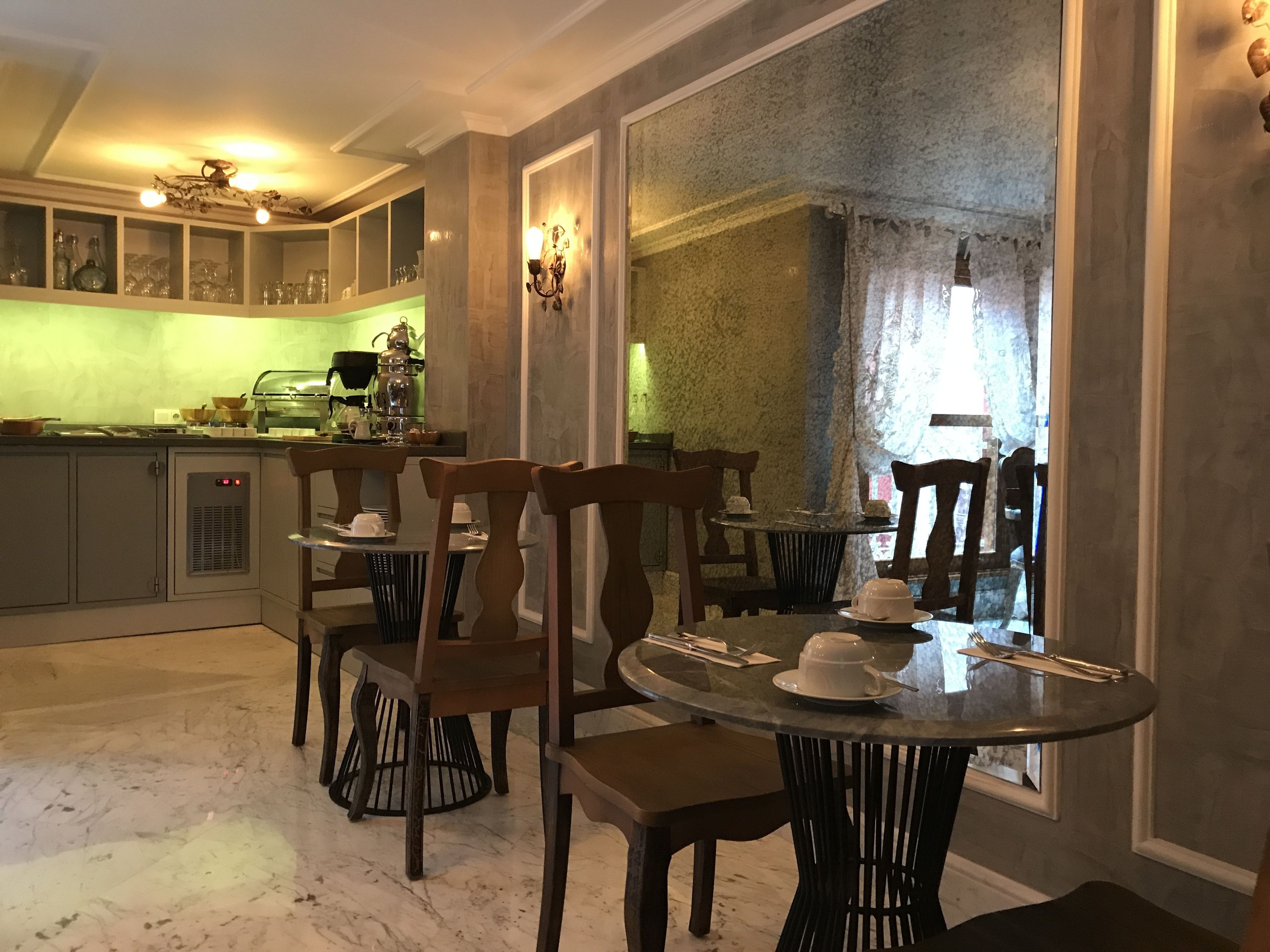 Uma sala de jantar com uma mesa redonda, cadeiras de madeira e vista através de uma grande janela.