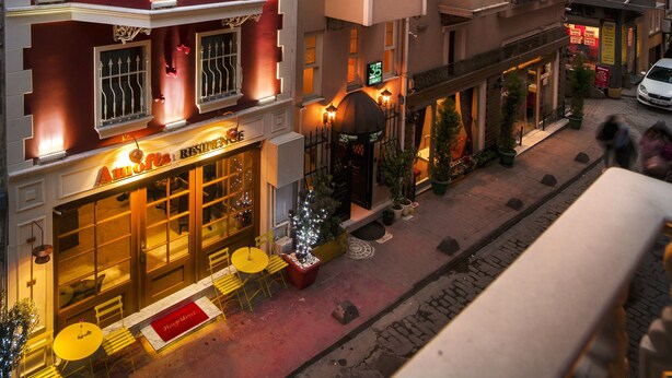 Ein mehrstöckiges Hotel mit Restaurant im Erdgeschoss, Außenbereich und roter Fassade.