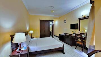 A hotel room with a bed, desk, chair, and a television.
