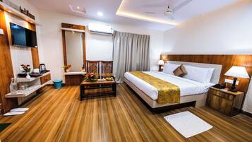 A hotel room with a bed, bedside tables, a TV, a desk, and a chair.