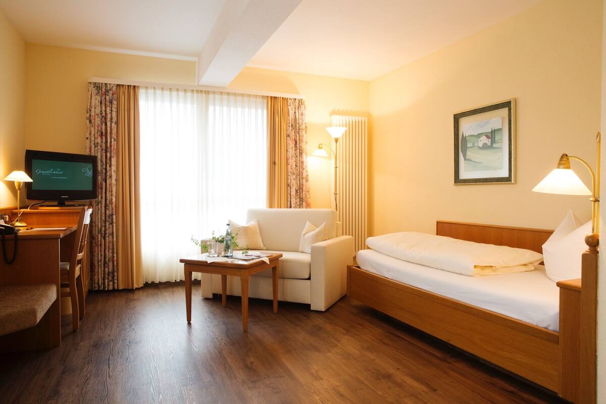 Een hotelkamer met een houten bed, een bank, een bureau met een computer en een televisie.