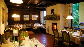 Un restaurant avec des poutres en bois, des carreaux de sol hexagonaux et des tables dressées pour le dîner.