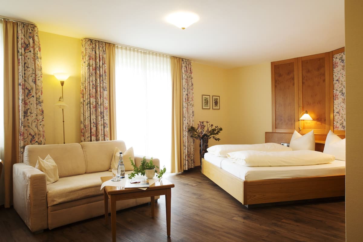 Een hotelkamer met een bed, een sofa, een tafeltje en een nachtkastje.