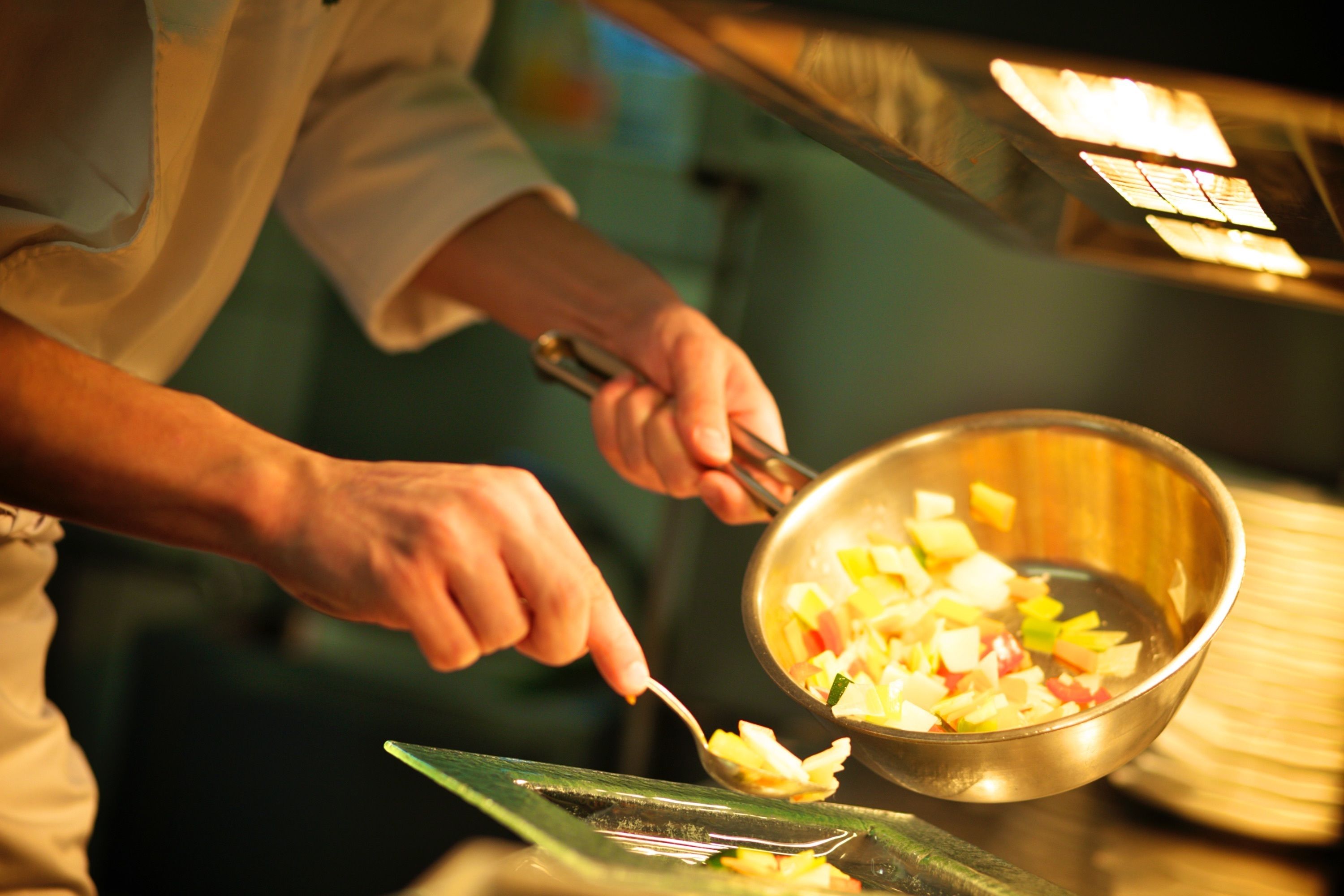 A person preparing food, using a spoon and a metal bowl.