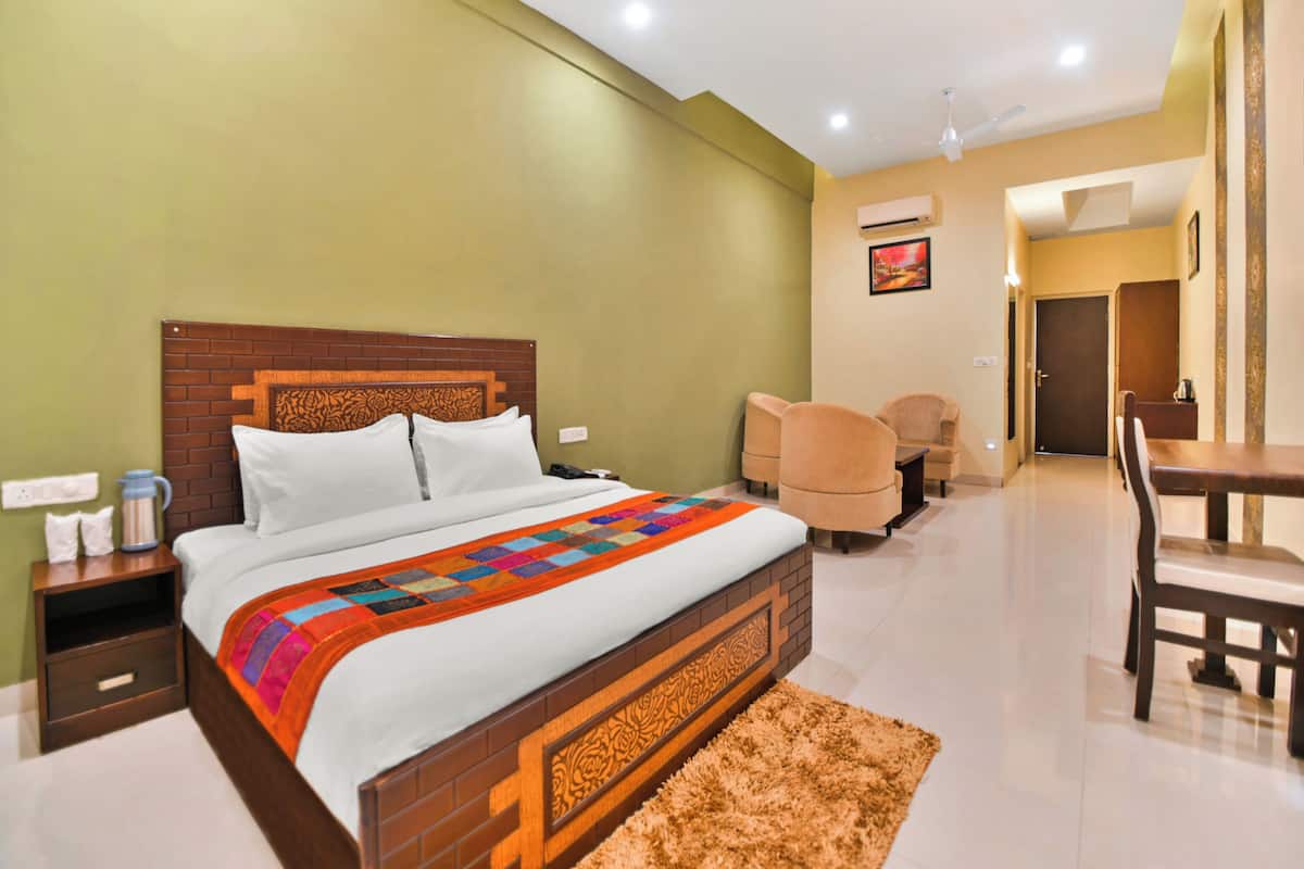 Habitación de hotel con una cama grande, un cabecero de madera, un escritorio y dos sillas.
