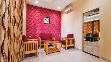 A living room with a red patterned wall, a ceiling fan, and a view into another room through a glass partition.