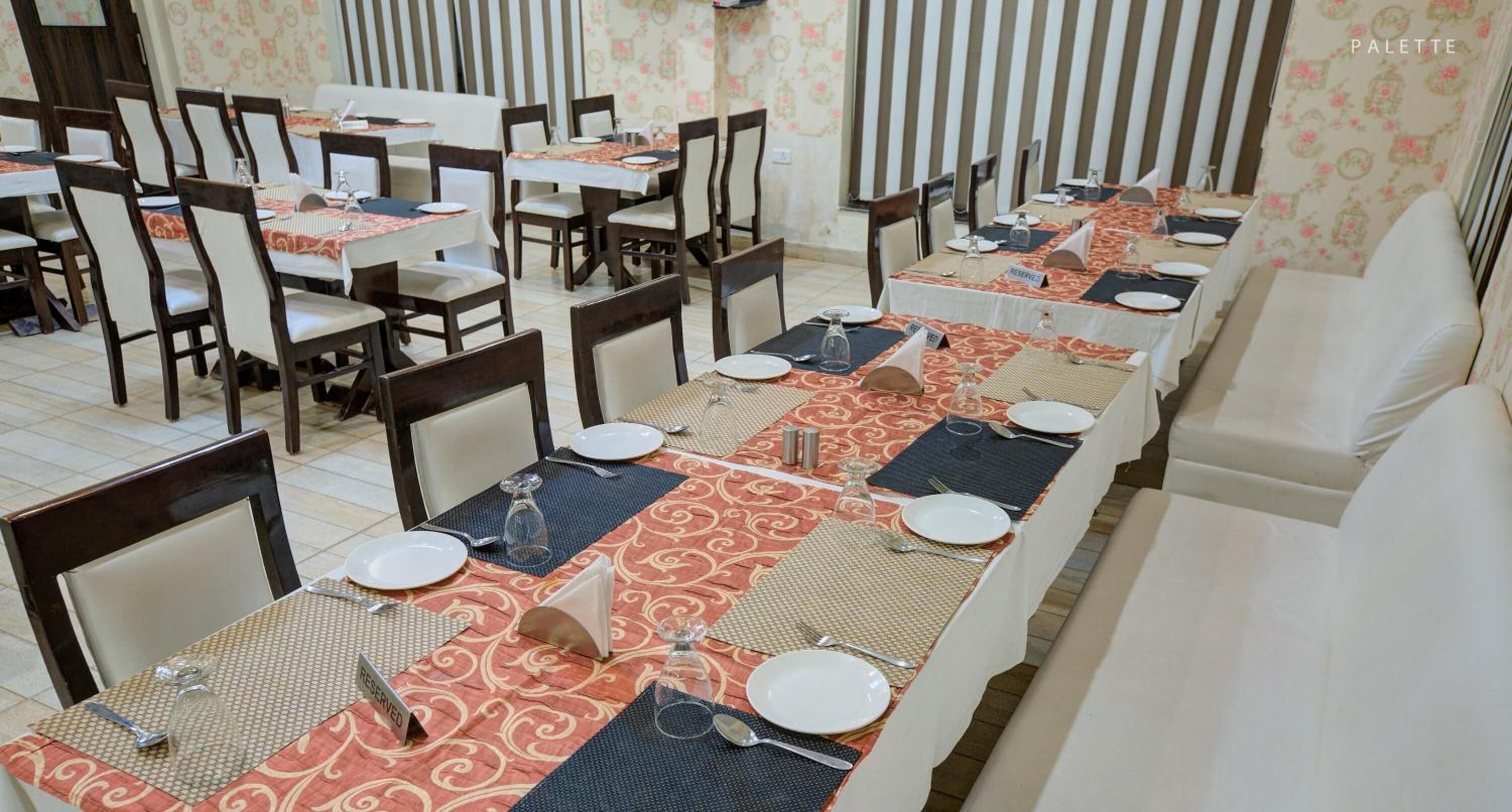 A dining area with tables set for multiple guests, each with place settings and name cards.
