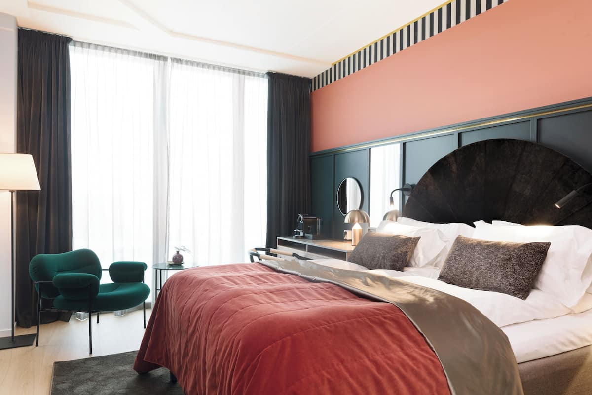 Habitación de hotel con una cama grande, un escritorio, una silla y vistas al exterior.