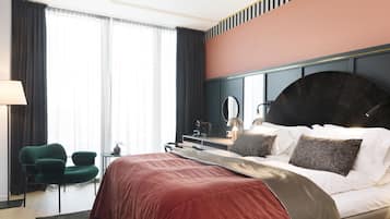 Une chambre d’hôtel avec un grand lit, un bureau, une chaise et une grande fenêtre avec des rideaux.