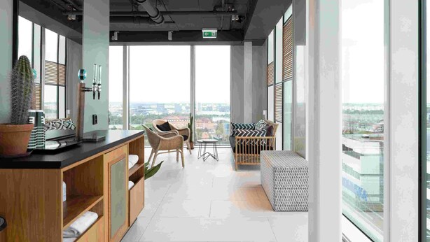 Een moderne lounge met een hoge plafond, grote ramen en uitzicht op de stad.