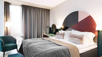 Habitación de hotel moderna con una cama grande, un escritorio, una silla y vistas a la ciudad.
