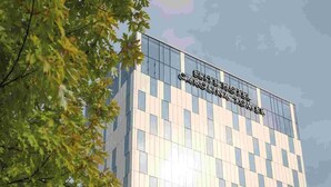 Een modern gebouw met een glazen gevel en een bord waarop 