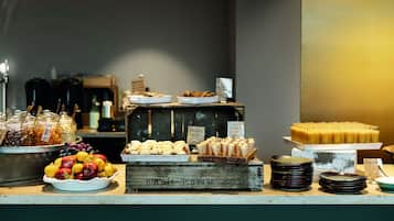 Buffet com diversas opções de comida, incluindo frutas, doces e sobremesas.