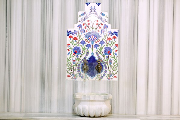 Un baño con pared de mármol y salpicadero decorado con azulejos.