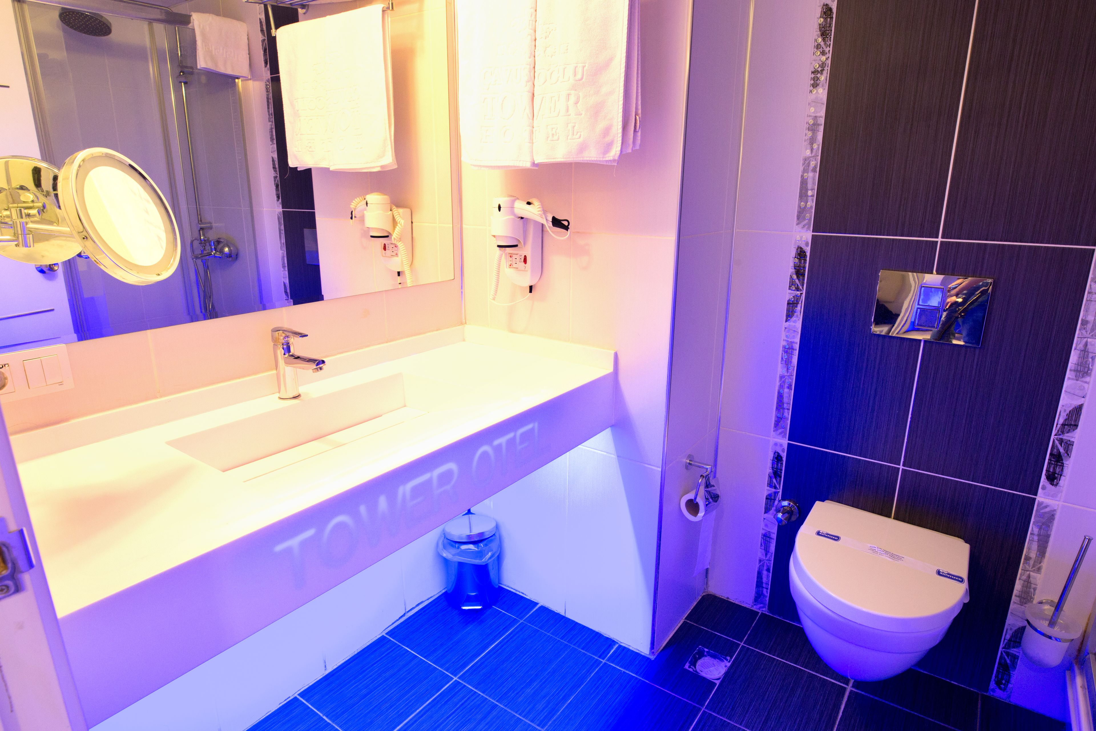 Une salle de bain avec un lavabo blanc, un miroir, des toilettes et un espace douche.
