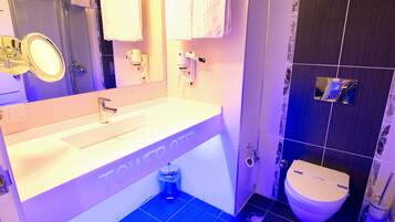 Une salle de bain avec un lavabo blanc, un miroir, des toilettes et un espace douche.
