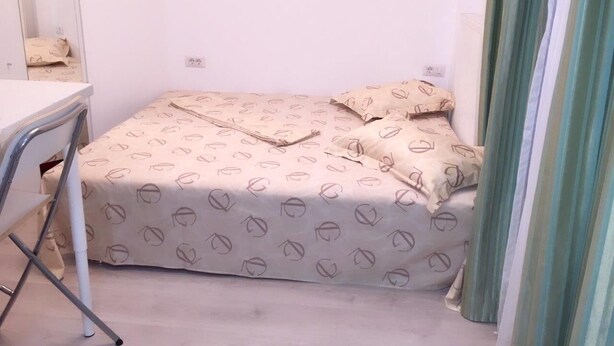 A small, neatly arranged bedroom with a bed, a chair, and a desk. - Casa Mendeleev (Bucharest)
